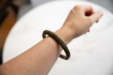 The antique African bronze bracelet with a rich patina, shown worn on an arm.
