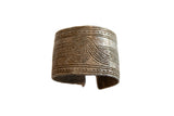 Antique African cuff bracelet with etched geometric spiral and crosshatch patterns.