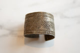 Intricate geometric patterns, including a central spiral, etched into an antique African cuff.
