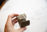 Antique African cuff bracelet held in hand, showing its scale and geometric etching.