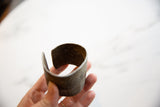 View of the antique African cuff's aged interior and substantial, curved shape.