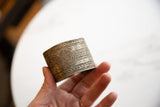 Antique African cuff bracelet with detailed geometric etchings and spiral design shown held in hand.