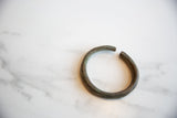 A detailed view of the aged patina on the rounded ends of the antique bronze cuff.
