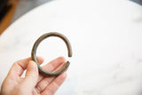 Antique African bracelet with an oxidized patina held in hand to show scale.