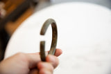 The solid C-shaped profile and dark patina of an antique African bracelet.
