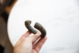 Profile view of the antique bronze cuff's thick, curved form and open ends.