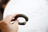 Detail of the curved terminal and textured patina on an antique bronze alloy cuff.