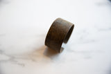 Close-up of the antique bronze alloy cuff, revealing its aged texture and faded detailing.