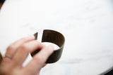 Hand holds antique bronze alloy cuff, revealing rich patina and open design.