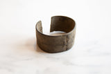 Profile view showing the open back and storied patina of an antique bronze cuff.