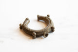 Detailed craftsmanship of an antique African bronze cuff's textured bands and spherical accents.