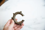 Aged bronze patina and handcrafted details on an antique African cuff bracelet held for scale.