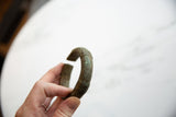 Close view of the antique bronze cuff's aged patina and incised surface details.