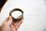 Antique oxidized bronze cuff bracelet held in a hand for scale.