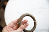 Antique African bronze cuff bracelet held to show the scale and texture of its open design.