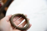 Antique African bronze bracelet held in hand, revealing its circular shape and aged patina.