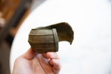 Hand holding a wide antique African bronze cuff, detailing its curved shape and oxidized texture.