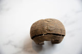 Angled detail of the antique African cuff's textured metal surface and raised geometric motif.