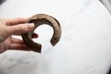 View of the antique African metal cuff's open C-shape and rustic, textured surface.