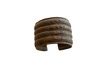 Antique African bronze alloy wide cuff bracelet with a rustic patina and raised geometric motifs.