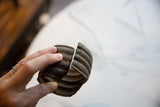 A hand holding the antique bronze cuff, showing its substantial thickness and aged surface.