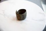 The dark, aged interior and open profile of the handmade African bronze cuff.