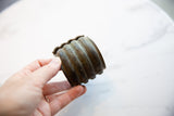 Hand holding the wide antique bronze cuff showing its ribbed form and time-worn patina.