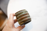 Antique African bronze cuff held in hand, showing its rich patina and ridged texture.