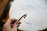 Aged patina and etched barber pole design on the curved bronze and copper bracelet.