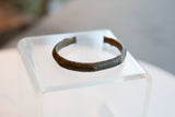 The curved shape and time-softened etched details of an antique bronze African cuff.
