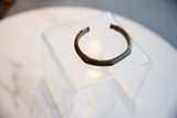 The aged patina and open C-shape of a collectible African bronze cuff bracelet.