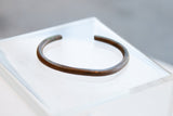 Aged patina and hand-forged character of a simplistic antique African copper cuff.