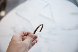 Antique copper cuff bracelet held to show its slender form and patina.