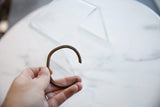 Antique African copper cuff bracelet held to show its simplistic C-shape and scale.