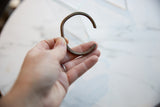Antique copper cuff bracelet held in hand to demonstrate its scale and form.