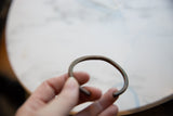 Antique copper cuff bracelet held to display its simple open form and dark patina.