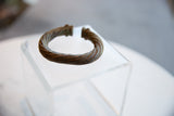Sculptural view of an antique African currency bracelet with a twisted design.