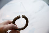 Close-up of the rounded ends and twisted, oxidized metal of an antique African bracelet.