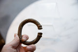 Antique African metal bracelet held in hand, showing its twisted form and aged patina.