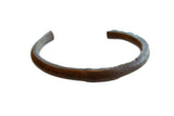 Antique African copper currency bracelet with a dark, weathered patina and handmade texture.