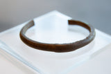 Side view of the antique copper bracelet's handmade texture and time-softened patina.