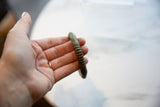 Ribbed texture and aged patina on an antique African bronze cuff held in hand.