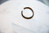 Angled view of the antique bronze bracelet's open C-shaped design and patina.