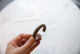 Hand holding an antique African bronze cuff to show its scale and weathered texture.