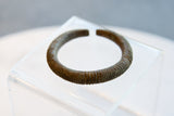 Aged patina on the incised geometric texture of an antique African bronze bracelet.