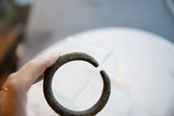 The antique African bronze bracelet held in hand to show its scale and geometric detailing.