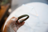 Antique bronze snake bracelet held in hand, highlighting its geometric detailed surface.