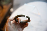 Antique bronze bracelet held in hand, showing its curved shape and tactile geometric texture.