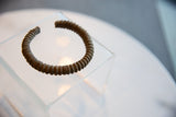 Angled view of an antique copper cuff bracelet showing its ridged, textured body.