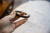 The ribbed texture and time-softened patina of an antique copper cuff held in hand.